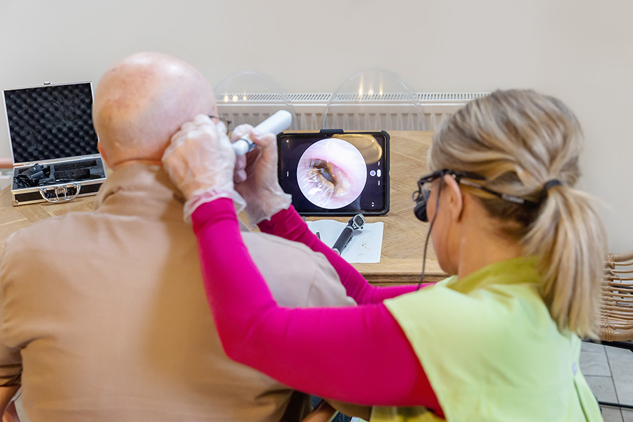 Earresistible mobile ear wax specialist in Nottingham carrying out treatment with client with digital camera visible of inside ear